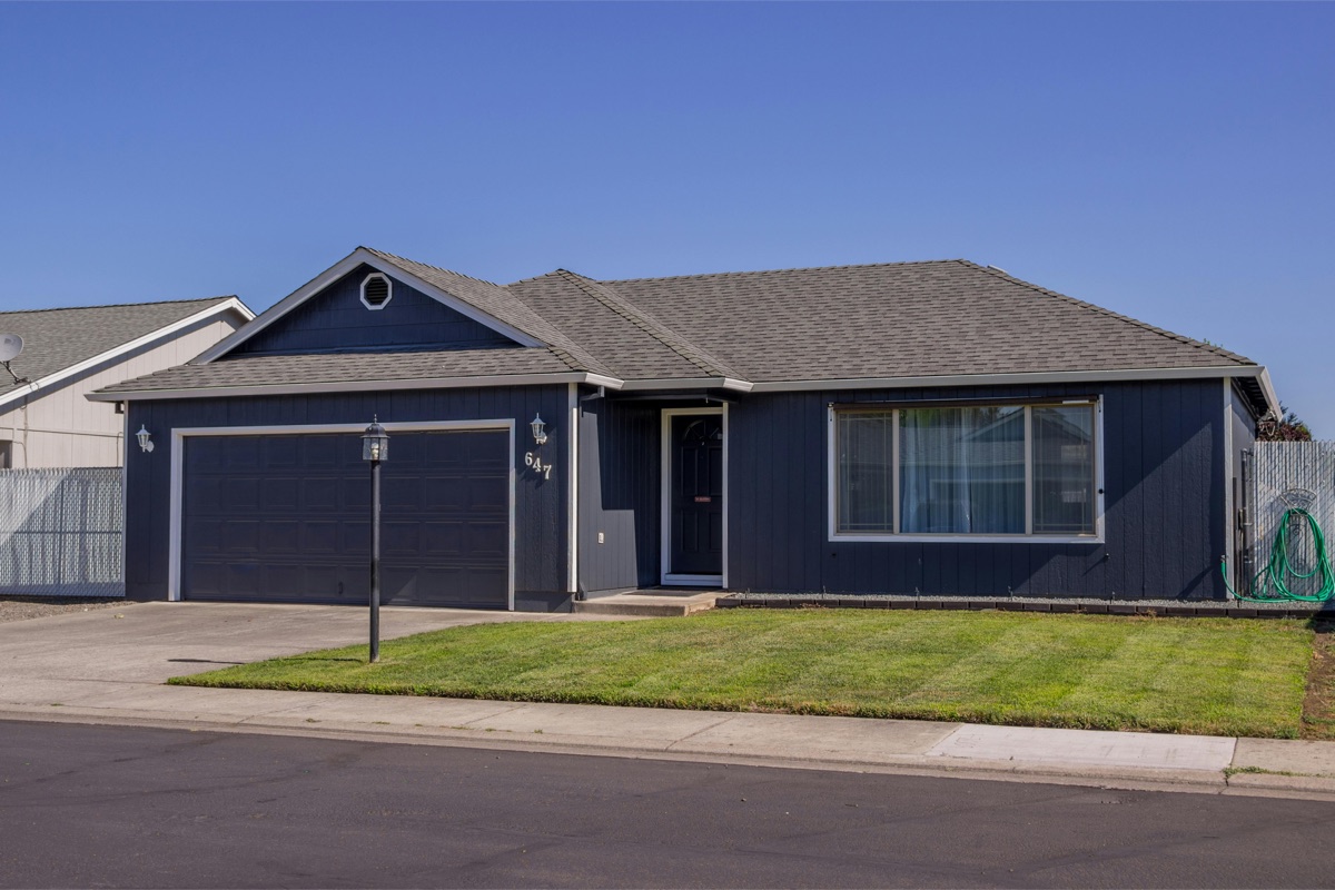 A single-story ranch home with newly installed architectural asphalt shingles and dark blue siding.