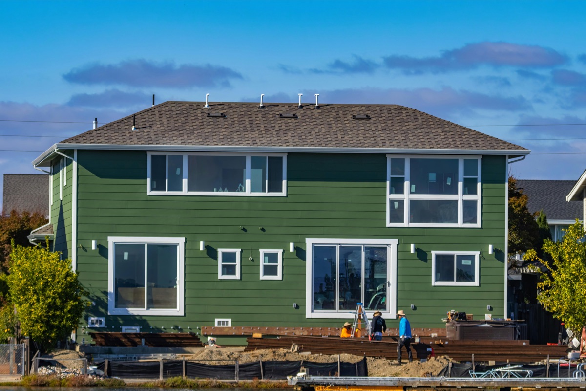 A two-story home with newly installed green James Hardie fiber cement siding and white-trimmed windows.